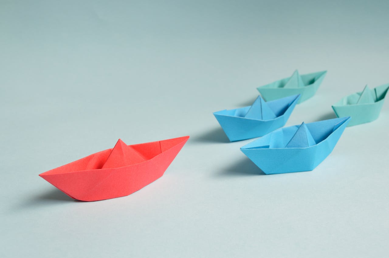 home-hero-1 Colorful origami paper boats arranged to depict leadership and teamwork concepts.